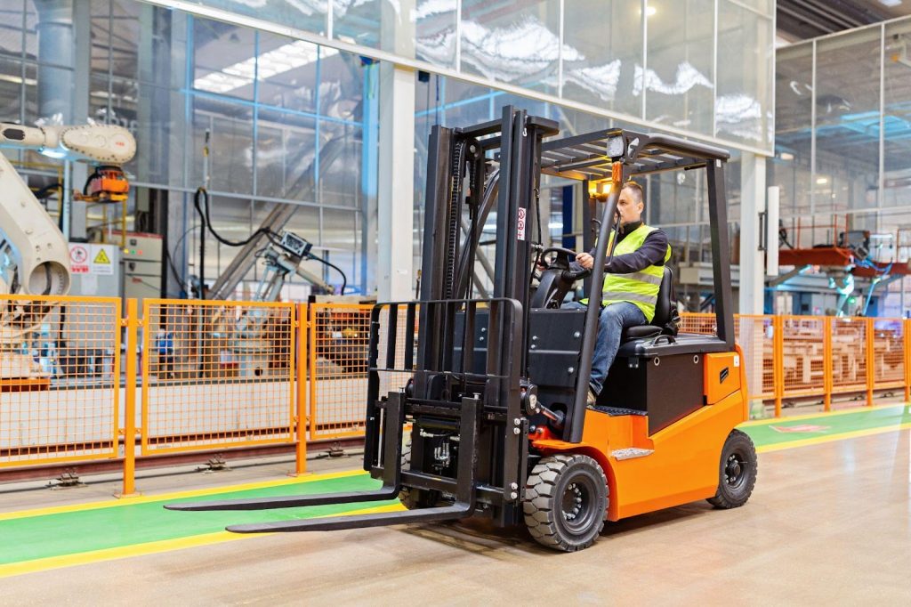 An industrial worker driving a forklift in a warehouse