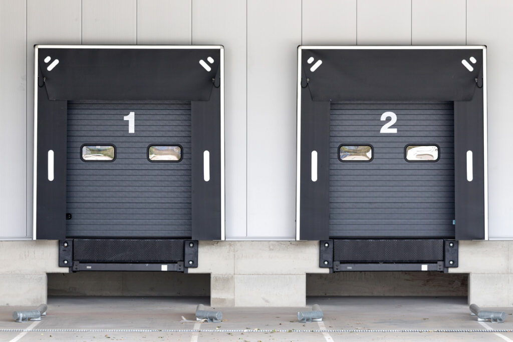 Two black loading docks with the numbers 1 and 2 written in white at a warehouse in Asheville.