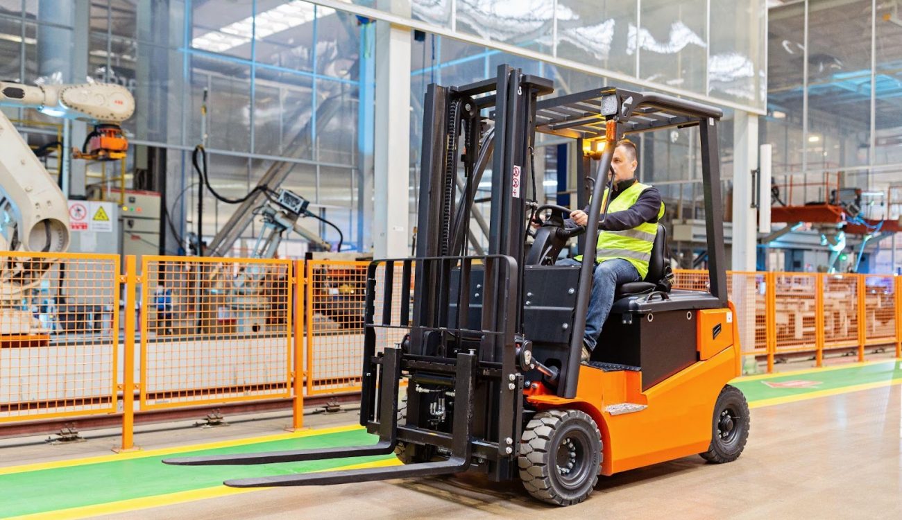 An industrial worker driving a forklift in a warehouse